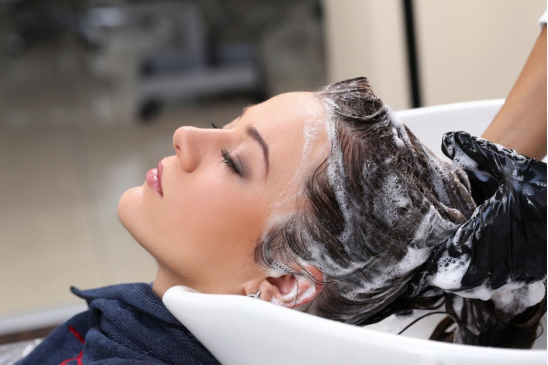A woman is washing her hair using a shampoo containing anionic surfactant ingredients